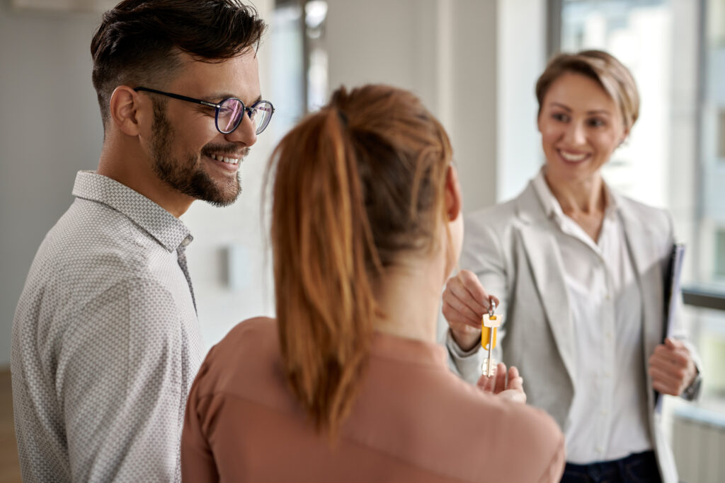 Young couple taking keys from their real estate agent for their new home purchase