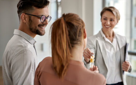 Young couple taking keys from their real estate agent for their new home purchase